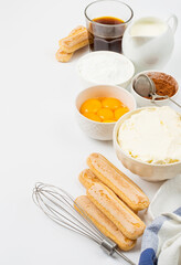 Ingredients for preparing the Italian dessert tiramisu. Savoiardi cookies, mascarpone, yolks, coffee, cream and cocoa on a light background.