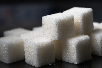 Pile of refined sugar cubes dark background.