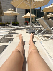 legs of woman sunbathing on beach or poolside of a resort	
