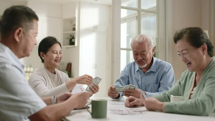 group of four happy senior asian people two old couples sitting at table at home playing cards - Powered by Adobe