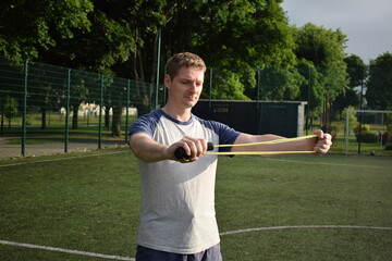 A young man in sportswear engages in a workout, using a sport tool for physical exercises on a...