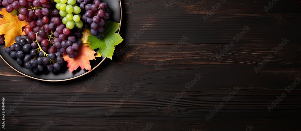 Poster top view of various types of grapes on vintage plate on black wooden surface. creative banner. copys