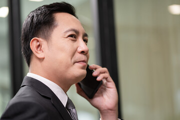 Asian businessman in formal suit talking on the phone with customer
