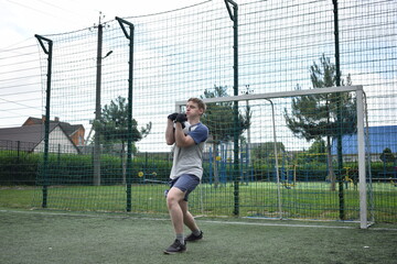 A young man in sportswear is playing soccer, training on a football pitch in the morning. Dedication and passion for the sport, the essence of morning exercise and practice outdoors