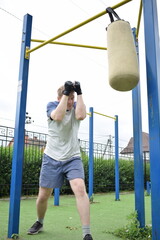 A dedicated young athlete boxing, puts in the hard work, training on gym equipment outdoors to...