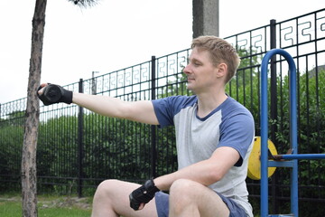 A young man in sportswear engages in a workout, using a sport tool for physical exercises on a...