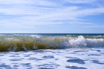 Sea wave close-up, water splash in the sea, sea foam against the sky on a summer sunny day