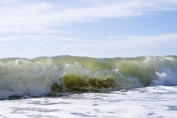Sea wave close-up, water splash in the sea, sea foam against the sky on a summer sunny day