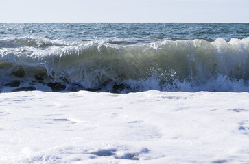 Sea wave close-up, water splash in the sea, sea foam against the sky on a summer sunny day