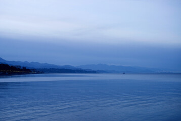 Sea blue evening landscape. Sea, sky, mountains, Kobuleti embankment in Georgia, and the city of Batumi visible on the horizon