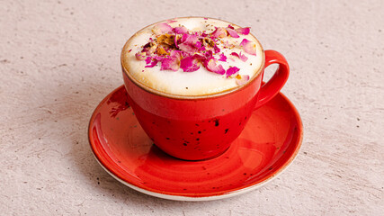 Cappuccino with rose petals in red cup isolated 