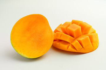 mango cut in half vertically next to mango cut lying down with rectangular cuts on a white background