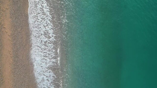 Amazing cenital aerial view of sea waves and sand on an empty beach during sunrise, 4k backgrounds 