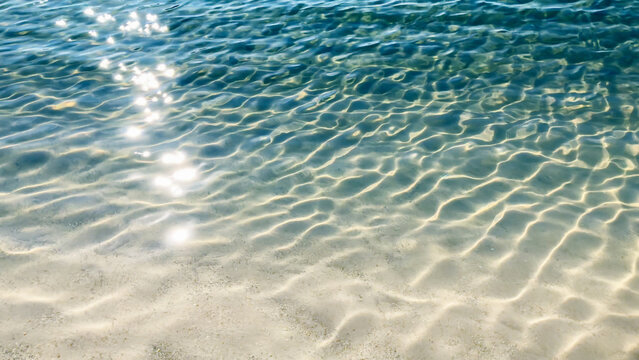 blue rippled water surface with glittering sun lights at the white sand beach, nature scene background for vacation, travel resort and wellbeing in summertime outdoors