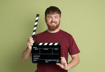 Making movie. Smiling man with clapperboard on green background