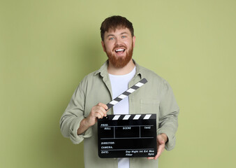 Making movie. Smiling man with clapperboard on green background