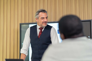 A man is giving a presentation in front of a large screen. The presentation is about graphs and...