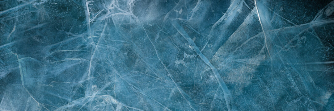 Abstract natural ice texture. Freezy ice surface. Blue backdrop with cracks and scratches on frozen water. Ice rink. Banner.