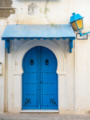 Traditional blue Tunisian metal door with a pattern in a white building in the city of Sidi Bou Said in Tunisia in the summer on a sunny day