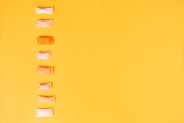 Multi-colored and different-flavored snus bags on a yellow background.