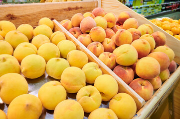 Two varieties of peaches displayed on fruit stands for sale at a local market.