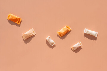 Snus sachets with different flavors on an orange background.