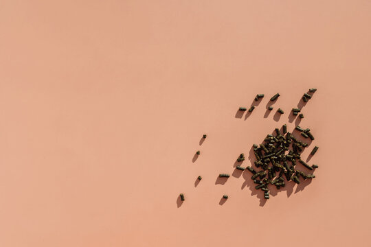 Scattered green and wet nasvay granules on a brown background.
