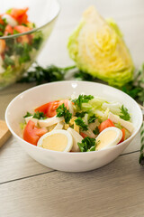 fresh vegetable salad, cabbage, tomatoes in a bowl on a wooden table