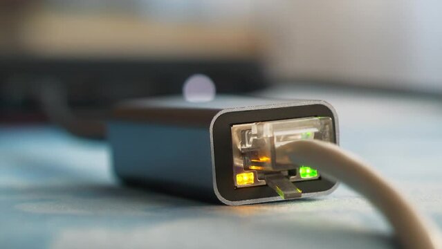 Ethernet cable adapter. Internet cable through an adapter connected to laptop. Working ethernet cable adapter with green LED and flashing yellow LED