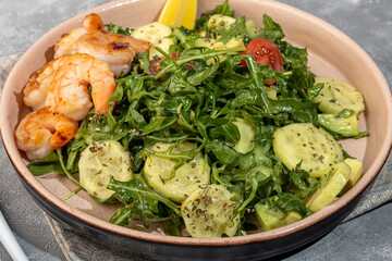 Salad with cucumbers and arugula, shrimp and cherry tomatoes in a light sauce.