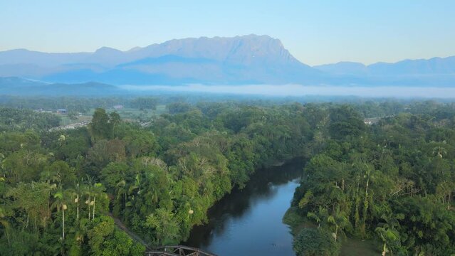 Voo sobre cidade de Morretes no Paran&aacute;, mostrando Pico Marumbi ao fundo na mata atl&acirc;ntica com neblina ao amanhecer, ponte f&eacute;rrea sobre o rio nhundiaquara