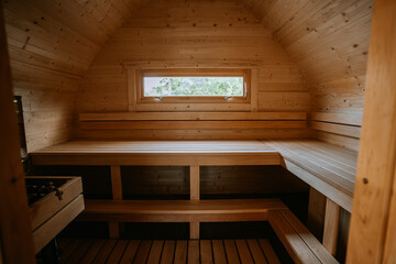 Cozy wooden sauna interior with benches, window, and soft natural light. Warm, inviting atmosphere for relaxation.