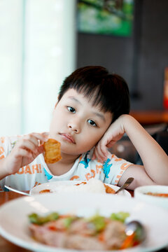 Cute asian boy eating Chicken Nugget by self. Background. Copy space.	