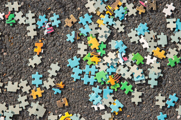 A background image of pile of mixed colorful jigsaw .Puzzle pieces set scattered on the gray...