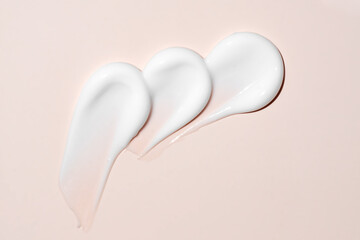 cream stroke isolated on beige background. White drops cream smear smudge sample. face or body skincare product swatch. showcase of the product