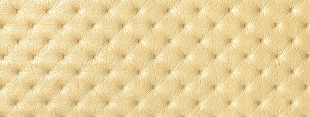 Texture of light golden leather background with capitone pattern, macro. Yellow textile of retro Chesterfield style.
