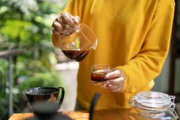 pouring black coffee from a glass carafe into a glass.