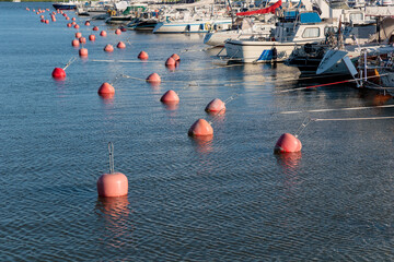 Buoys in Marina sea port, sailboats moored at the dock and reflected in the sea, harbor, sea and blue sky, sunny day © gudzar