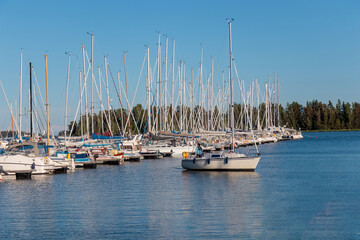 Fototapeta premium Marina sea port, sailboats moored at the dock and reflected in the sea, harbor, sea and blue sky, sunny day
