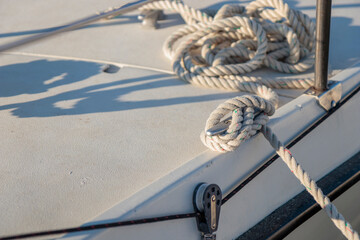 Fototapeta premium White rope tied to the mooring cleat of a sailboat, sunny light