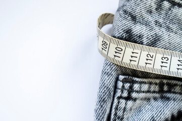 Measuring tape with jeans isolated on white. Weight loss concept