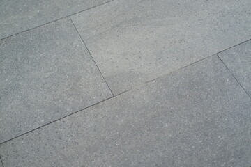 Fototapeta premium Close up of a grey tile floor with a slightly textured surface. 