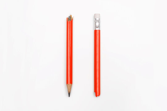 A broken pencil is centered on a white horizontal background. Close-up of a red graphite pencil broken into two halves. Emotions, stress, aggression, problems in school, problems at work - Powered by Adobe
