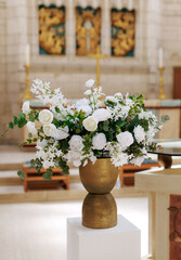 White flowers in a pot decorating the room. White artificial flowers as a decorative element in a golden pot