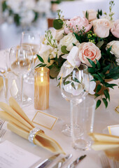 Dining table with beautiful table settings and floral decorations. Beautifully decorated table in a restaurant. Silver cutlery, fresh flowers and clear glasses decorate the table in a restaurant