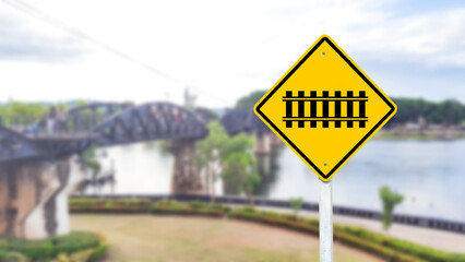 A black train and railway crossing symbol is prominently displayed on a bright yellow sign.