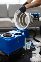 Filling the extractor machine with water. Using extractor to clean sofa at home. Pouring detergent...