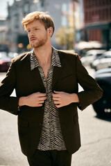 A stylish redhead man strolling down the city street.