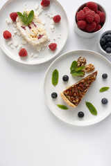 Plates with desserts close-up on a white background. Copy space. Pecan pie, meringue roll and chocolate cake are decorated with berries and mint leaves. Breakfast and tea