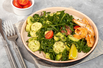 Salad with cucumbers and arugula, shrimp and cherry tomatoes in a light sauce.